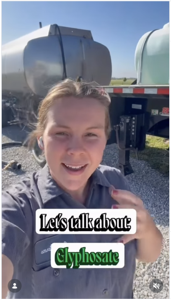 A woman in a work shirt stands outdoors in front of large agricultural tanks, smiling at the camera. Text on the image reads: “Let’s talk about: Glyphosate and its role in modern agriculture.”.